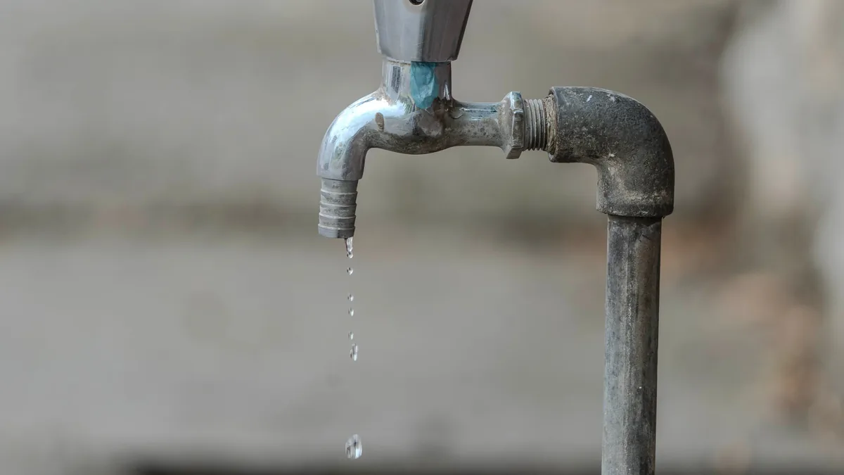 A metal faucet with water dripping from it.