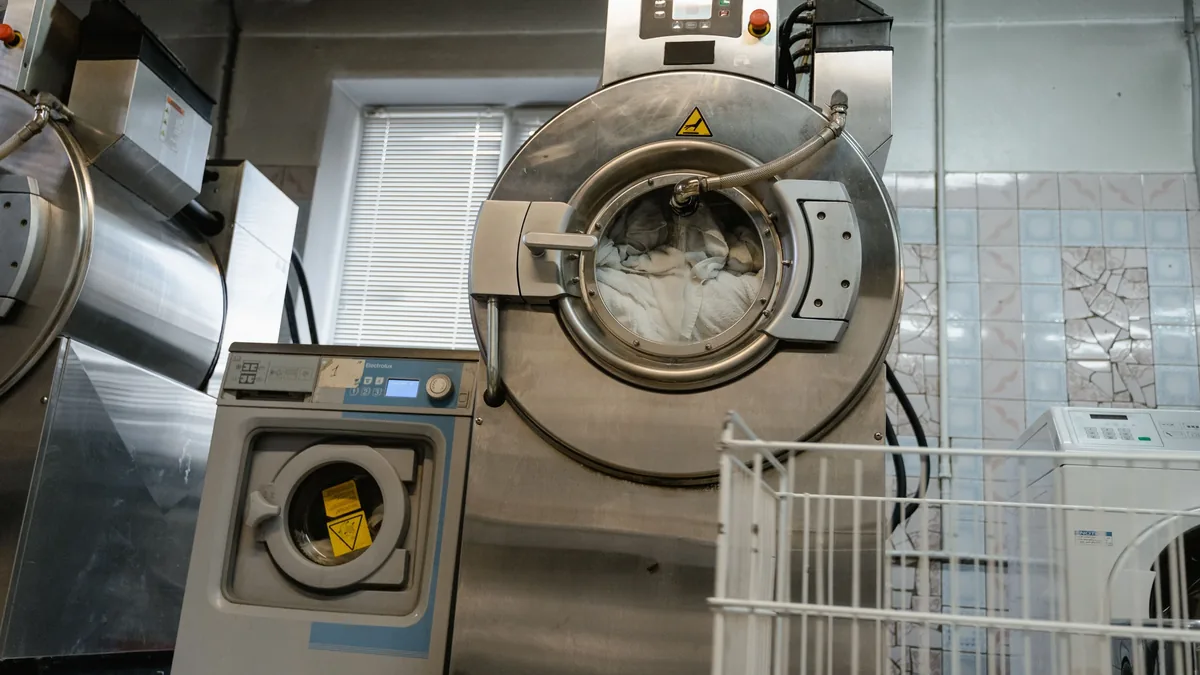 A large industrial washing machine and a smaller domestic washing machine in a laundry room.