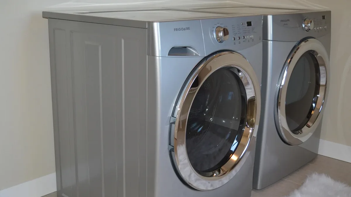 A silver front-loading washing machine and dryer side-by-side in a laundry room.